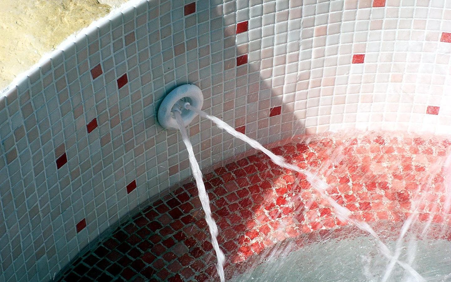 Interior del spa revestido de gresite blanco y rojo, con las boquillas de hidromasaje